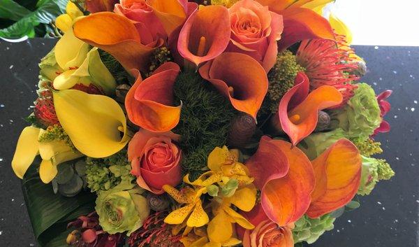 Tropical arrangement with orange mango Calla Lilies, yellow Dendrobium and orange Cushion Protea