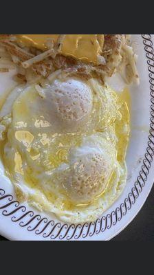 Burnt hash browns and eggs swimming in fake butter.