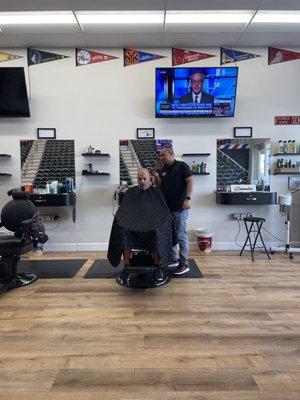 Ramiro giving a client a fade and a shave .