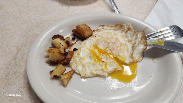 One single fried egg with potatoes from the ordered platter