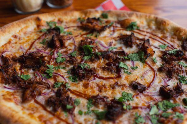 BBQ Pizza: Our house shredded BBQ pulled pork, BBQ sauce, mozzarella, shaved red onions, and cilantro.