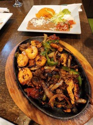 Steak, chicken, and shrimp fajitas with rice and beans.