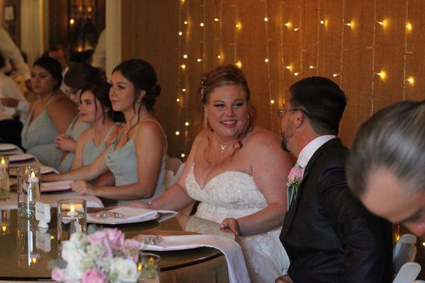 Head table in front of burlap wall with twinkle lights