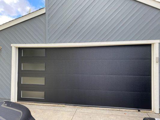 Installed an Flush Panel collection garage door in black color and obscure glass.