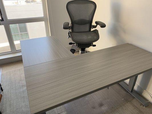 L-shaped electric sit-stand desk built, delivered and assembled by the QCA team