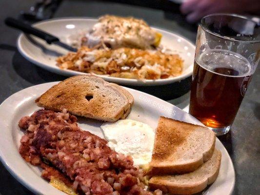 Corn beef hash with one egg and rye toast up front, biscuits and gravy special with hash browns in the back.