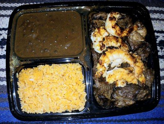 Shrimp  and steak platter with black beans  and Spanish rice.