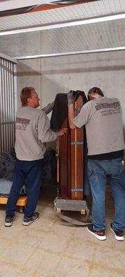 Two of your crew moving a baby grand piano  in our customers storage