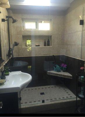 Custom tile shower with niche, corner seat and heavy glass enclosure.