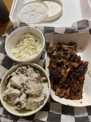 Pulled pork with cole slaw and potatoe salad sides.