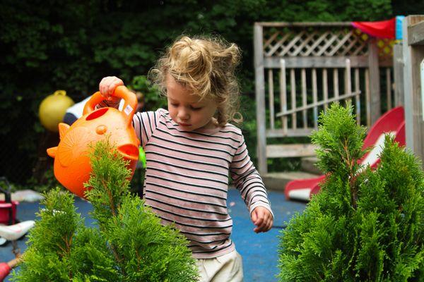 Kid watering plants on the playground.