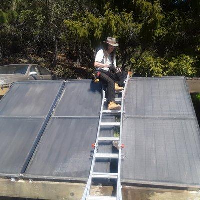 Gary effecting minor repairs on a ten year old solar water heating collector bank.