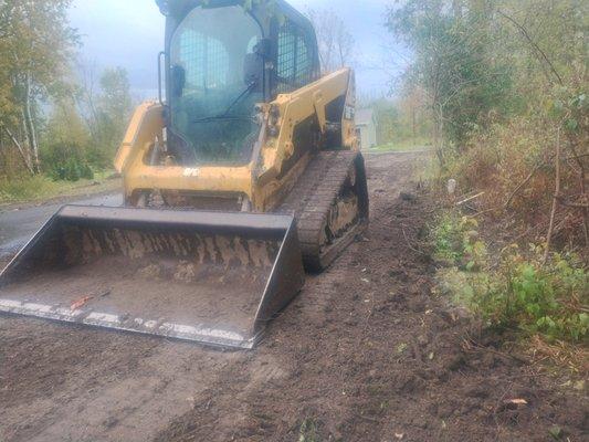 Cat 239d pictured grading raw soil