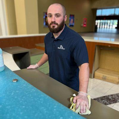 employee cleaning desk at a retail store office area