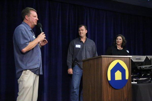 Two of our members stand right as VP of Multifamily Mentoring, John Ridgway, guides them through part of their Case Study presentation.