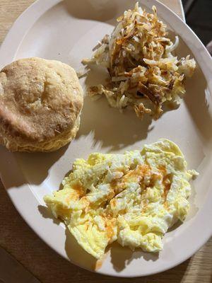 Eggs scrambled hard, hash browns, and a biscuit