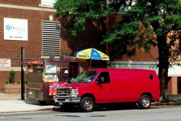 Victory Hot Dog Cart and Bistro. The table is behind the van, running from just before the umbrella to the tree.