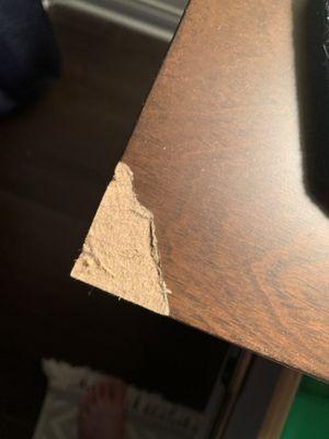 Edge of table top showing cardboard under thin laminate that chipped off on carpet!