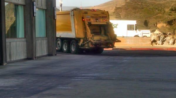 Truck leaving after not picking up mess of paper behind on sidewalk....