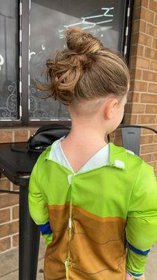 Haircut - child with hair up in a bun and undercut.