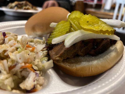 Sliced brisket with a side of coleslaw onions and pickle mild sauce on top