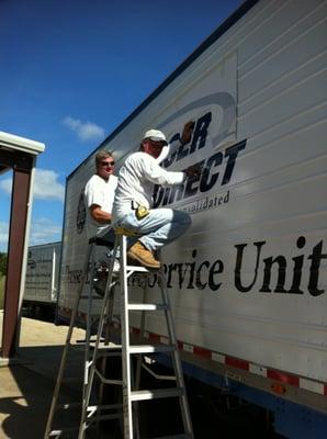 Gardner & Martin Installing Vinyl Lettering to the Side of a Trailer