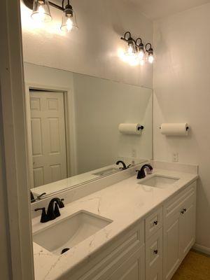 Restored bathroom with new cabinets, faucets,  lights, under mount sinks and quartz countertop. Countertop by Ventura Stone!