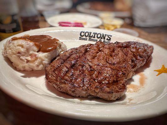 Ribeye cooked medium rare with mashed potatoes and gravy.