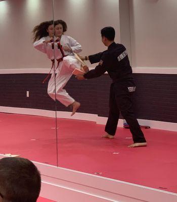 A student breaking a board with a flying side kick during their belt promotion test