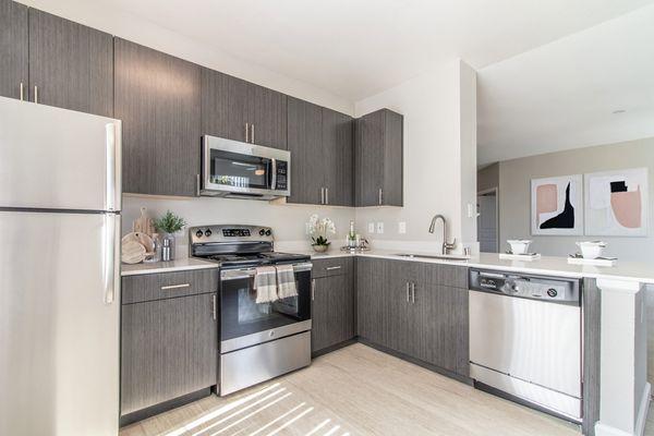 Spacious kitchen with hardwood-style vinyl floors, stainless steel appliances, and quartz countertops.