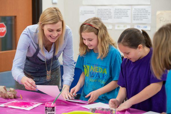 A teacher assists the students with the art lesson we provided for their fundraiser.