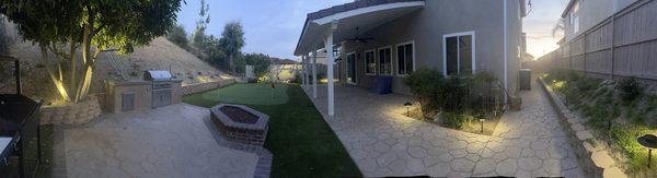 Backyard patio with lights, putting green, roses  and covered patio.