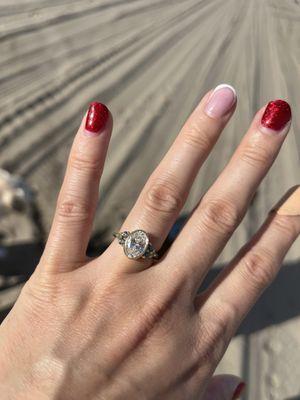 Oval diamond engagement ring set in a gold bezel band with sapphire and peridot side stones