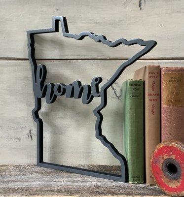 The state of Minnesota outline with the words - Home - carved in the center.