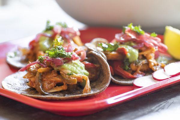 Vegan Jackfruit Tacos with roasted poblano, avocado tomatillo salsa, crispy jalapeño, blue corn tortilla