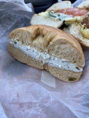 Jalapeño cheddar bagel with garlic and herb cream cheese and a quechee on a sesame bagel.