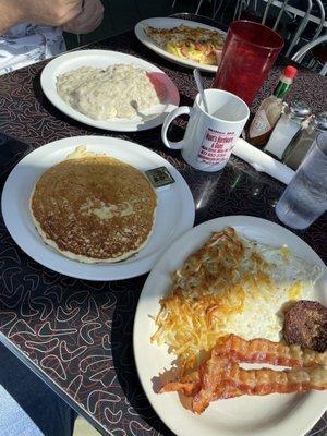 Pancakes with eggs, hash browns, bacon, and a sausage patty.