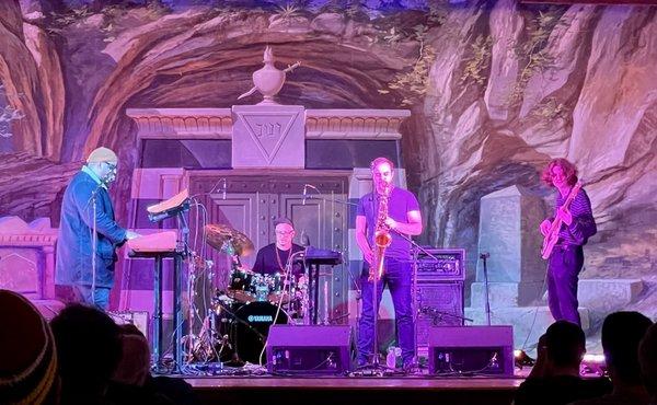 Jaron Marshall and band playing on stage with another gorgeous painted backdrop behind them