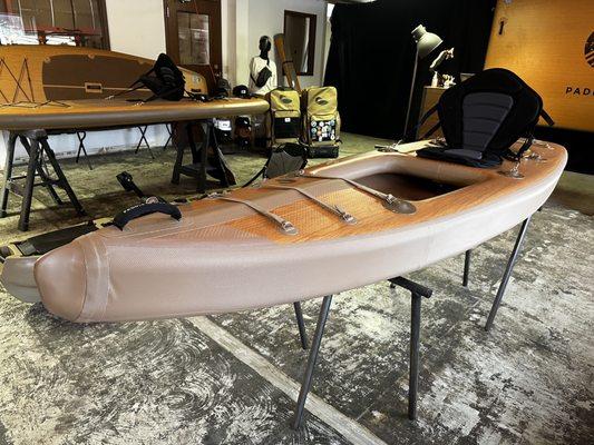 Inflatable single seat kayak next to a stand up paddle board