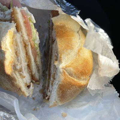 Chicken cutlet on a roll with lettuce, tomato and mayo.