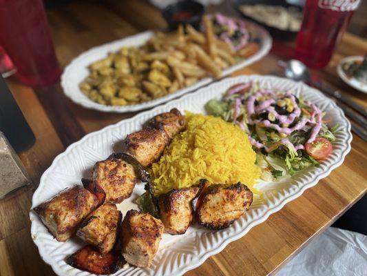 Front = chicken shish kabob with rice; back = chicken curry with a side of fries