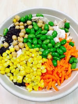 Custom brown rice bowl with chicken, black beans, chick peas, edamame, corn, and carrots