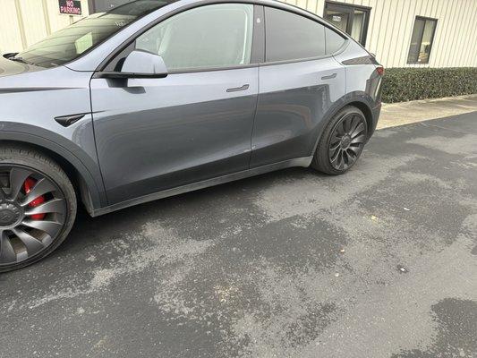 Tesla Y with textured wrap below doors with arch at front to address road grime paint damage.