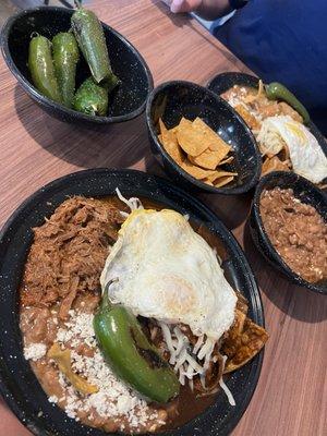 Chilaquiles de Mole and Chilaquiles de Chicharon with an egg over easy, refried beans, and chiles toreados.