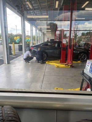 Car tire being checked by both employees