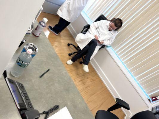 Staff worker sitting and playing on her phone while her coworker citing her own inability to find a file in their system.