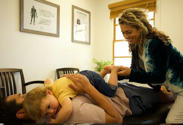 Dr. Catherine adjusting a little one while she is comfortable laying on her dad.