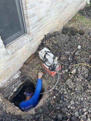 Pressing pilings under the perimeter beam of a slab foundation repair