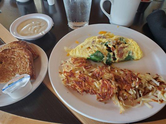 Bacon, spinach, and cheese omelet with hasbrowns, toast, and a side of gravy.