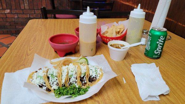 Tacos de bistec with avocado and cheese, served with charro beans, chips and salsa.